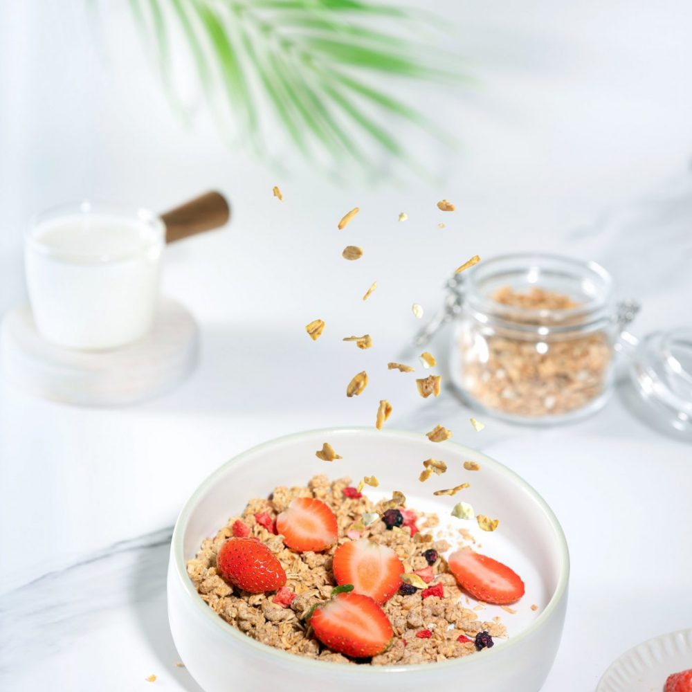 Granola with yogurt and strawberry for healthy breakfast on a white marble table